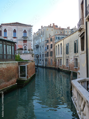 イタリア・ヴェネツィアにて小さな運河の水路とパステルトーンの家の壁