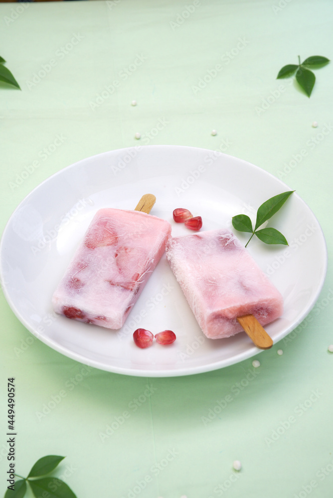 Pomegranate seeds and two ice creams on a white plate with light green background, cool and relieving heat, essential for summer Pomegranate seeds and two ice creams on a white plate with light green background, cool and relieving heat, essential for summer