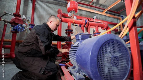 A water pumping station engineer repairs the water supply compressor engine. photo