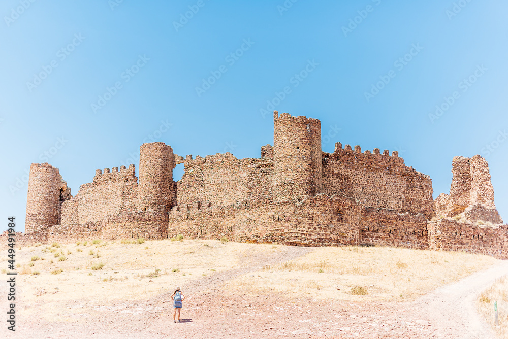 Ancient walled castle with a woman standing in front of it