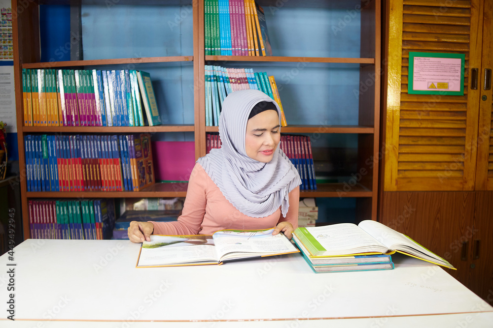 islamic woman reading book on the desk in her workroom islamic woman reading book on the desk in her workroom