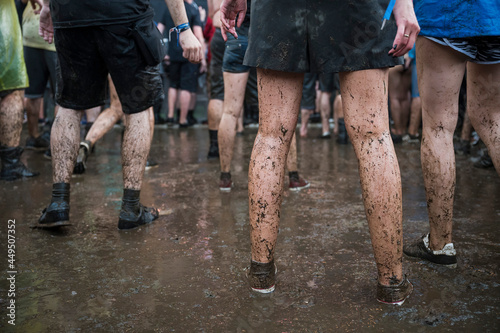 Dirty legs of people dancing in the mud during concert. photo