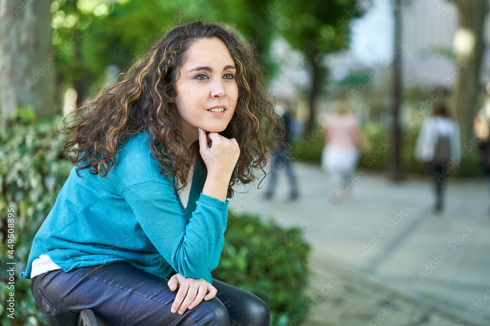 young woman thinking sitting on a bench in a turquoise blue sweater young woman thinking sitting on a bench in a turquoise blue sweater