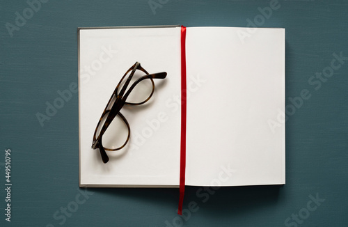 notebook with space for text, red tab, glasses, on a painted background, photo from above