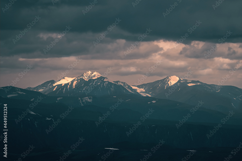 Fototapeta premium Wonderful dramatic landscape with big snowy mountain peaks above low clouds. Atmospheric large snow mountain tops in cloudy sky.