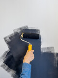 Woman painting a wall in black. Copy space.