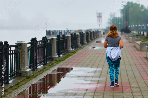 Female runner. Fitness girl jogging, healthy lifestyle and physical fitness in the city. Morning after rain. Puddles on the sidewalk. Selective focus.