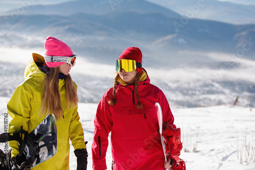 Two Woman snowboarders walks on the snowy mountain.