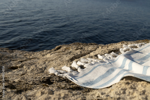 Striped white-blue towel on the rock against blue sea.Empty space for design