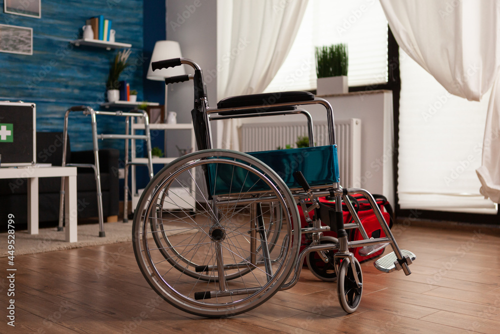 Hospital medial wheelchair standing in empty living room with nobody in it ready for healthcare therapy assistance. Social support nursing services at home. Disability rehabilitation