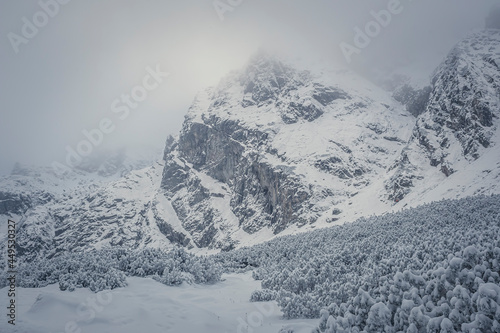Kościelec Peak in the clouds, High Tatra Mountains, Poland. Rocks and crags covered with fresh snow. Selective focus on the details, blurred background. photo
