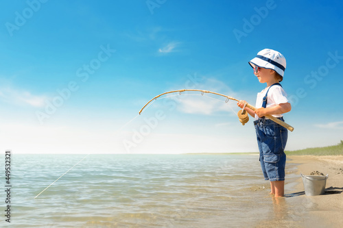 Kid play on the beach on a hot sunny day. Little girl stands barefoot on the beach in the sand and dreams of catching a big fish.