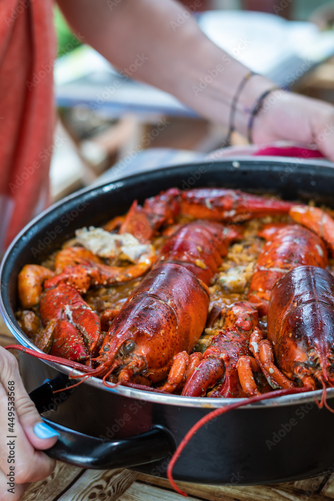 Woman taking Spanish paella with lobster. Close up