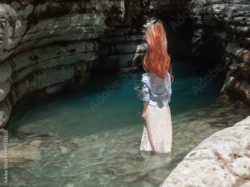 Girl doing a wave of long hair while standing in the water among the canyons photo