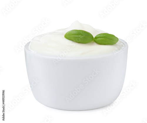 Delicious sour cream with basil in bowl isolated on white