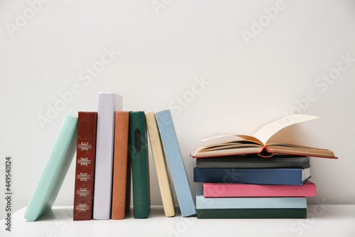 Different books on white table near light grey wall