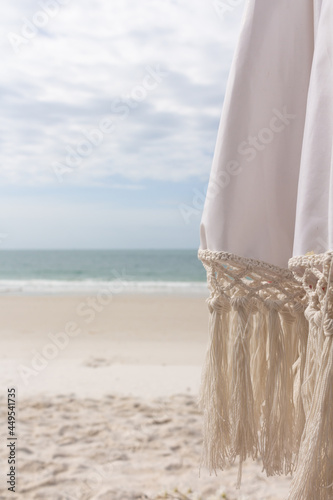 Close up of umbrella on white sand beach and sea background with copy space.