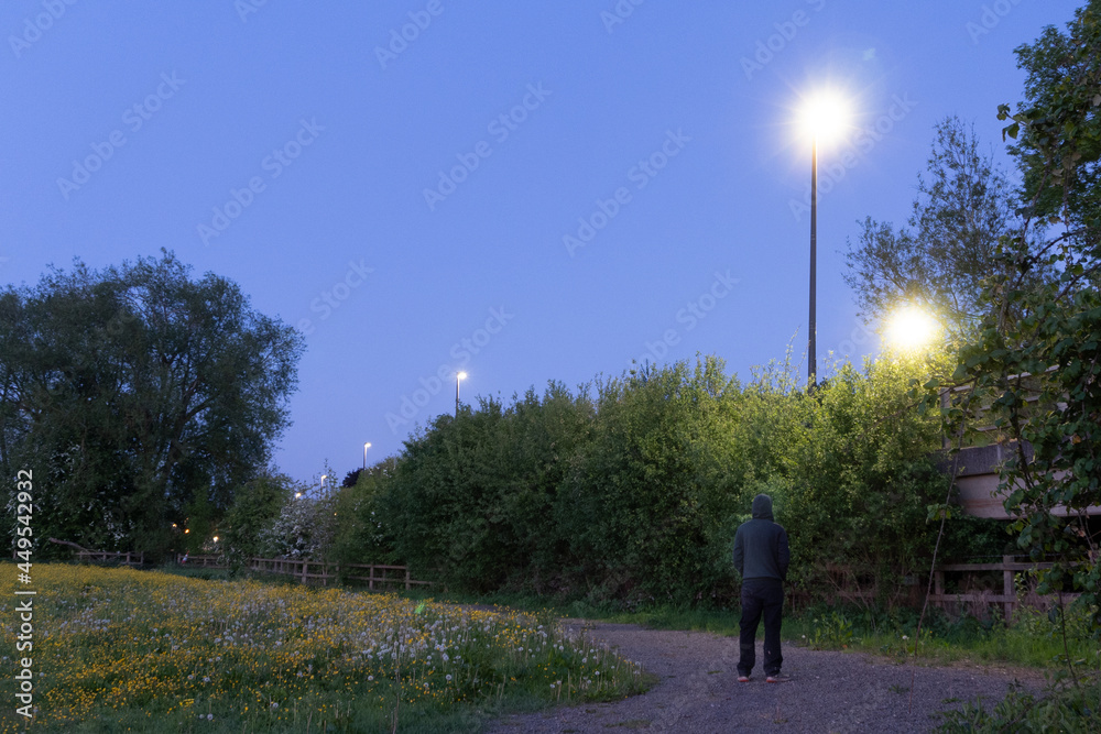 A mysterious hooded man, looking up at a street light. On a spring evening. A mysterious hooded man, looking up at a street light. On a spring evening.