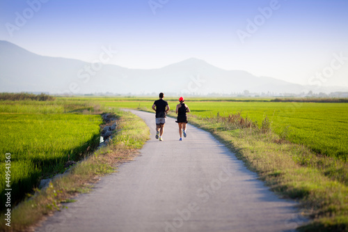 Pareja corriendo al atardecer entre campos de arroz