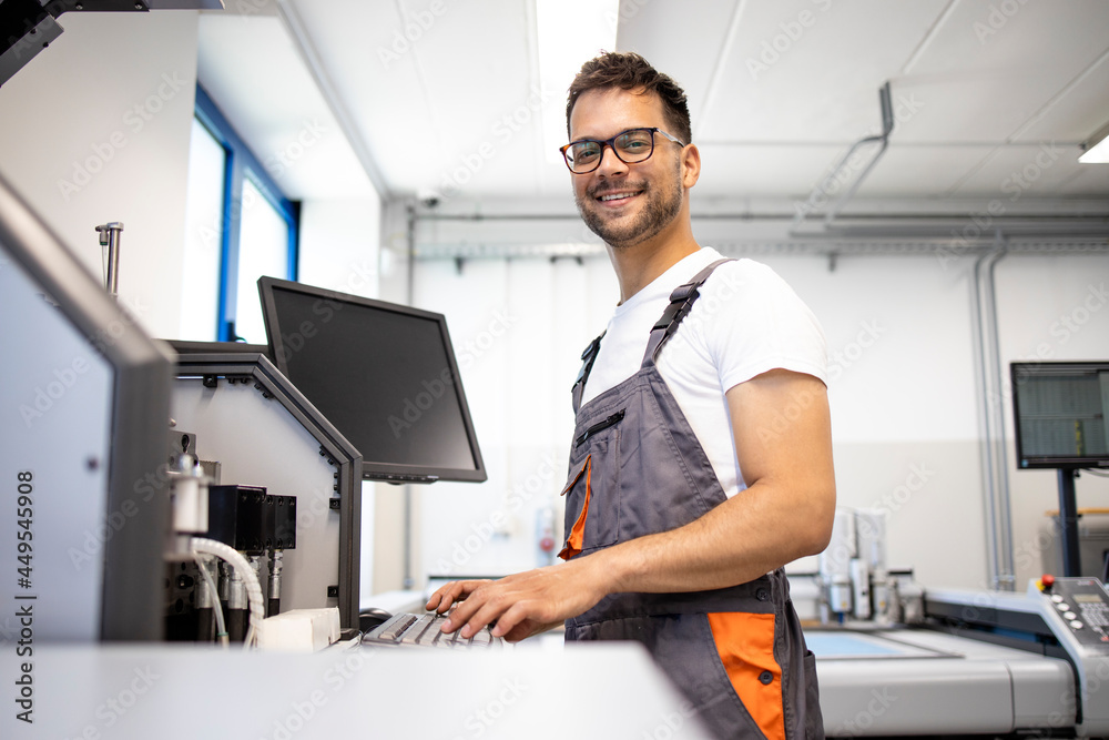 Fototapeta premium Portrait of smiling worker standing by industrial production machine.