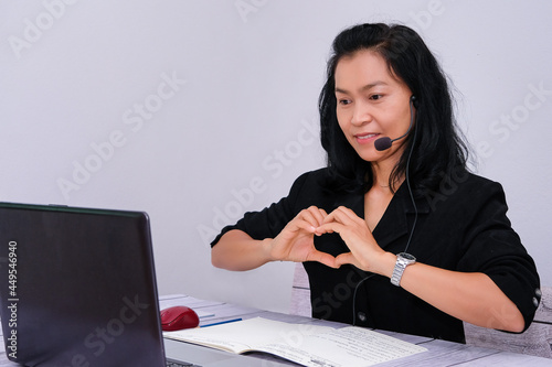 Asian young businesswoman student-teacher tutor wear wireless headset video conference show sign language computer talk by webcam learn to teach online chat, distance webinar online teaching concept