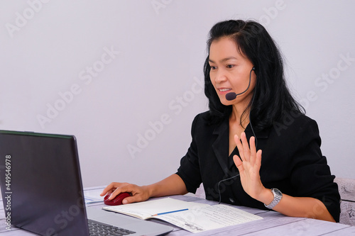 Asian young businesswoman student-teacher tutor wear wireless headset video conference show sign language computer talk by webcam learn to teach online chat, distance webinar online teaching concept