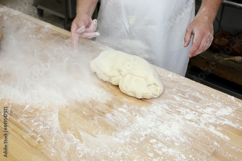 Baker kneading dough on wooden table