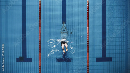 Aerial Top View Male Swimmer Jumping, Diving into Swimming Pool. Professional Athlete Winning World Championship. Top Down View.