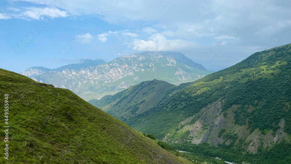 Amazing landscapes of North Ossetia. Majestic mountains, green hills, blue skies and white clouds.