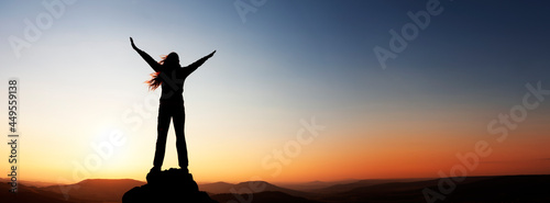 Frau mit erhobenen Armen über dem Horizont bei Sonnenuntergang