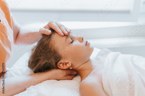 real doctor osteopath hands does physiological and emotional therapy for eight year old kid girl. pediatric osteopathy treatment session. alternative medicine. taking care of the child's health