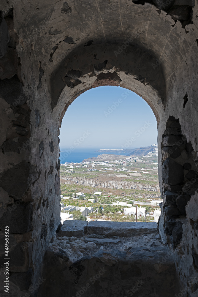 view of White and blue top of buildings from a window in Pyrgos Santorini, Greece with blue sky in a sunny warm day in July 2021.