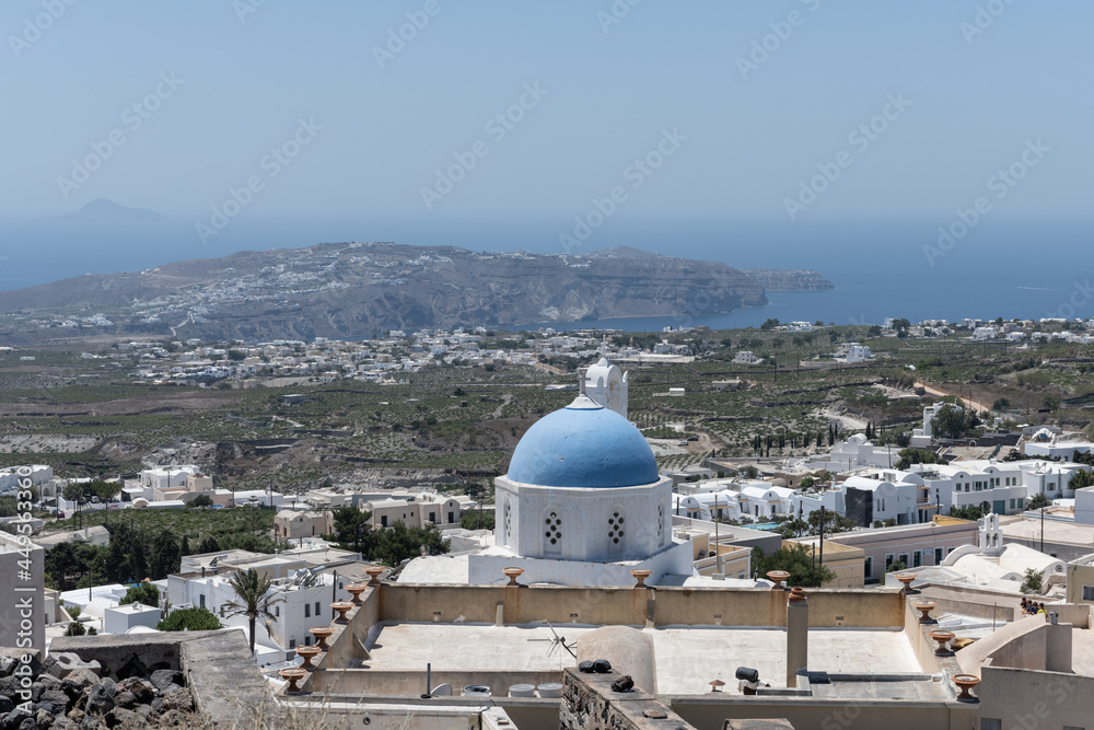 White and blue top of buildings in Pyrgos Santorini, Greece with blue sky in a sunny warm day in July 2021.