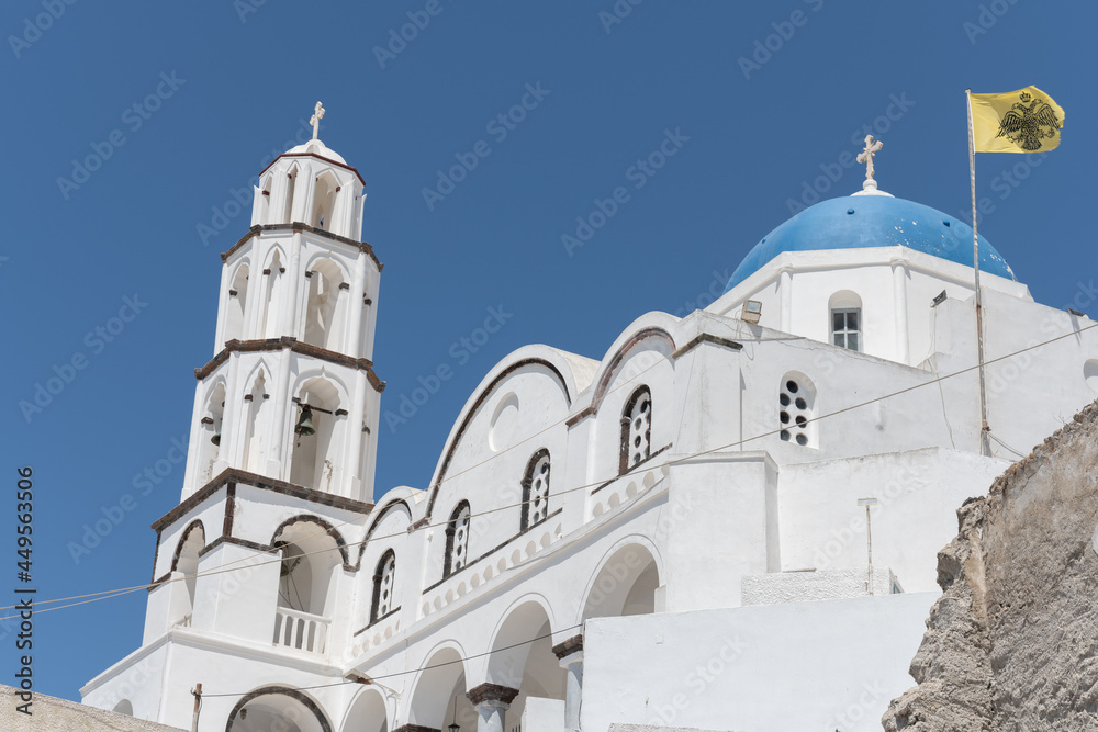 White and blue top of buildings in Pyrgos Santorini, Greece with blue sky in a sunny warm day in July 2021.