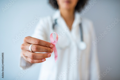 Doctor with pink ribbon and stethoscope on white background, closeup. Breast cancer awareness. Female Doctor Holds Pink Ribbon, International Breast Cancer Day October 7 - Image photo