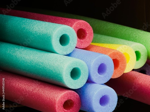 Pool noodles stacked in a pile of bright colors.