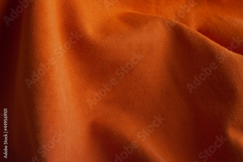 Texture of knitted fabric with waves. Orange cotton background. Fiber surface. Canvas backdrop.