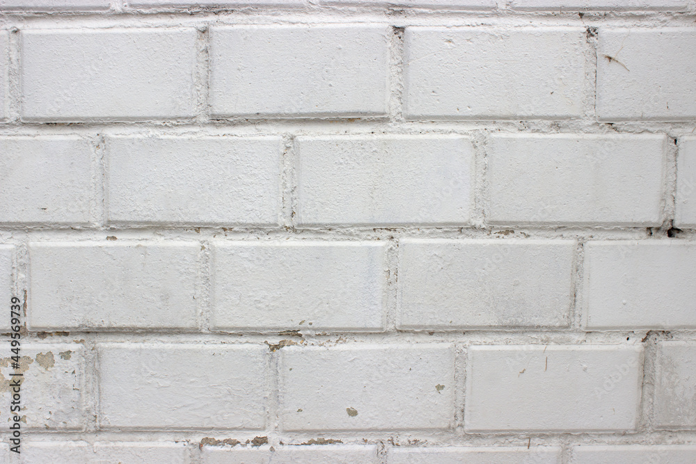 Background white brick wall close-up with peeling paint on the left side Background white brick wall close-up with peeling paint on the left side