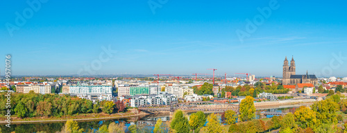 Panoramic bird view at Cathedral of Magdeburg, modern luxury houses and bridge during golden Autumn at blue sky and sunny day, Magdeburg, Germany. Concept of historical architecture heritage.