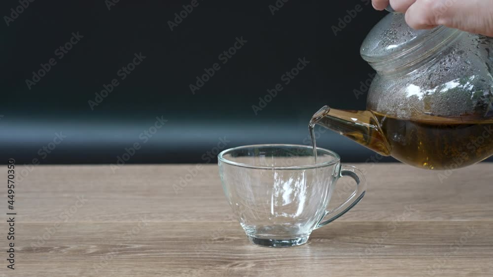 slow motion of hands of person pouring black hot tea from teapot into teacup slow motion of hands of person pouring black hot tea from teapot into teacup