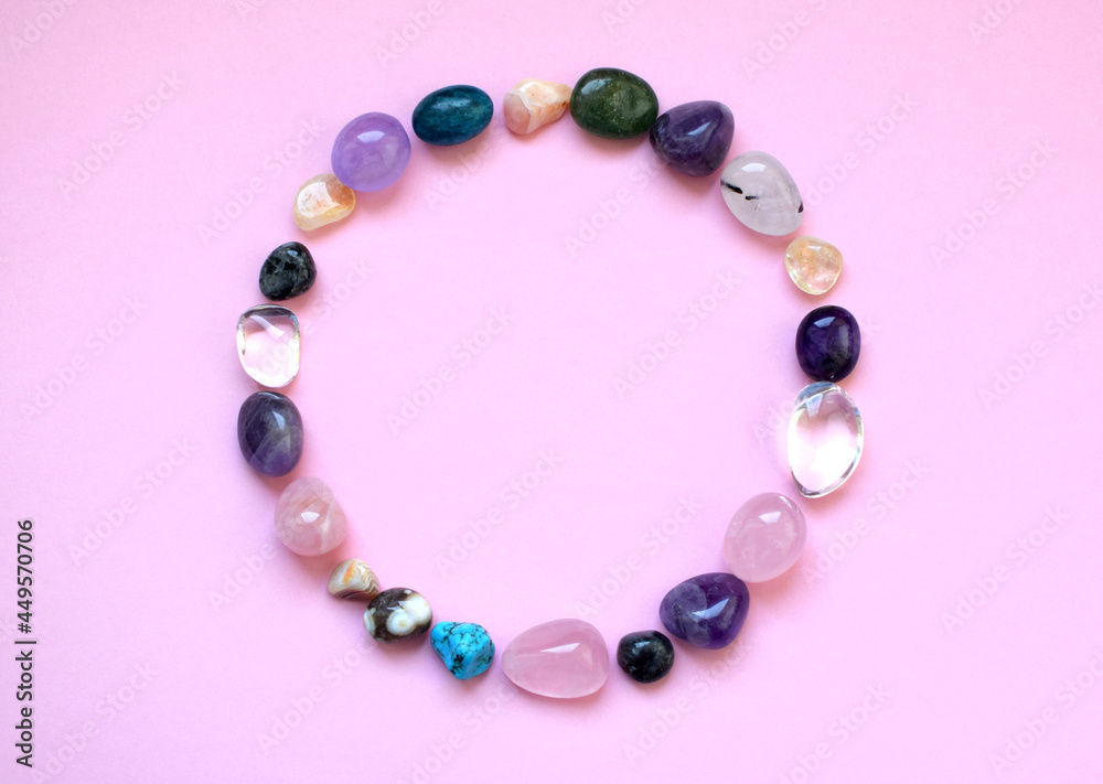 The circle is lined with natural minerals. Semi-precious stones of different colors, raw and processed. Amethyst, rose quartz, agate, apatite, aventurine on a pink background The circle is lined with natural minerals. Semi-precious stones of different colors, raw and processed. Amethyst, rose quartz, agate, apatite, aventurine on a pink background