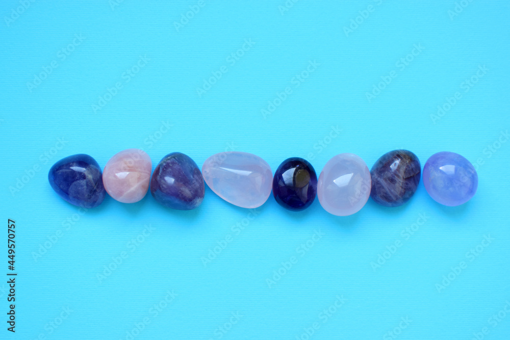 Gems of various colors. Amethyst and rose quartz on blue background. Gems of various colors. Amethyst and rose quartz on blue background.