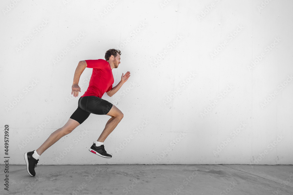 Fitness running man runner profile on wall white background. Male sports athlete sprinting with hiit high intensity interval training workout wearing compression sportswear clothes.