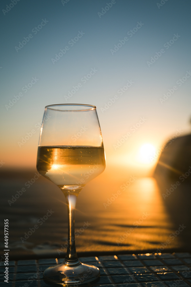 Close-up of glass with champagne wine. Sunset sky on background.