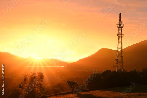 Fényképezés Telecommunication mast on golden sunset background in the mountains
