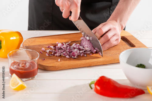 Close-up on chef's hands cutting onion with a santoku knife photo