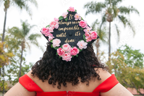 Canvas-taulu Grad girl wearing a graduation cap decorated with pink flowers and golden letters