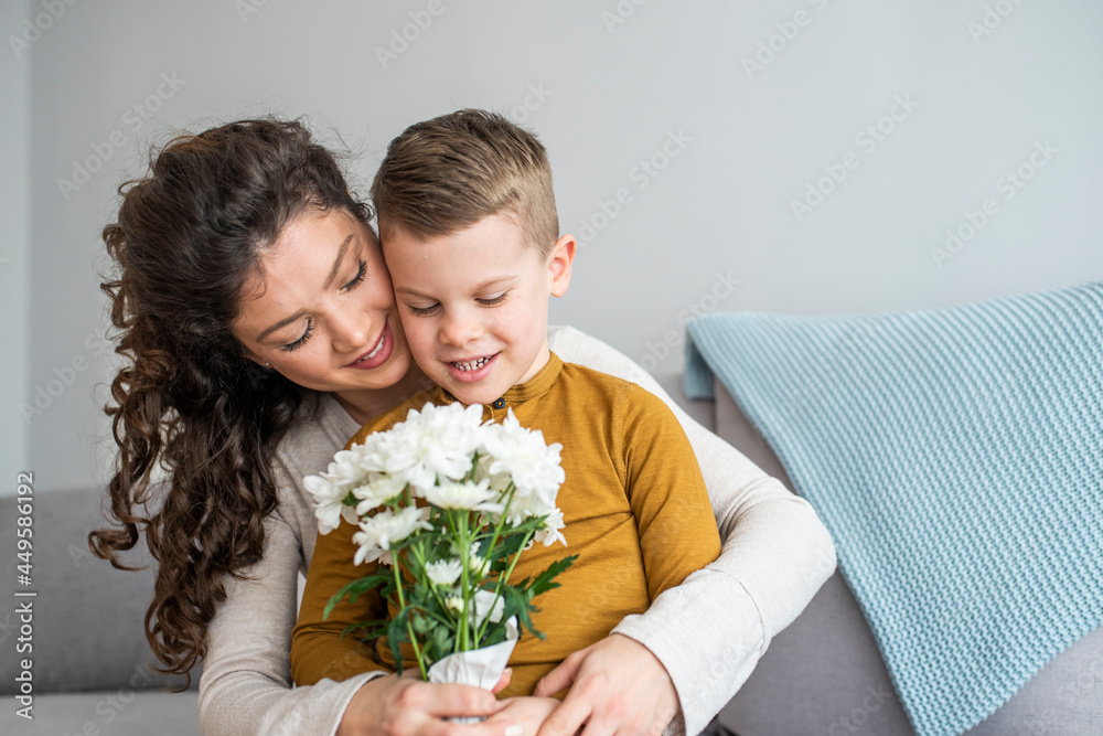 Mother and her little son with bouquet of flowers, Happy family mom and kid kissing and hugging. Mother's day gift. Son hugging happy mother with flowers. Mother and her little son with bouquet of flowers, Happy family mom and kid kissing and hugging. Mother's day gift. Son hugging happy mother with flowers.