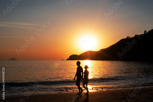 silhueta de casal caminhando em por do sol na praia de Maresias