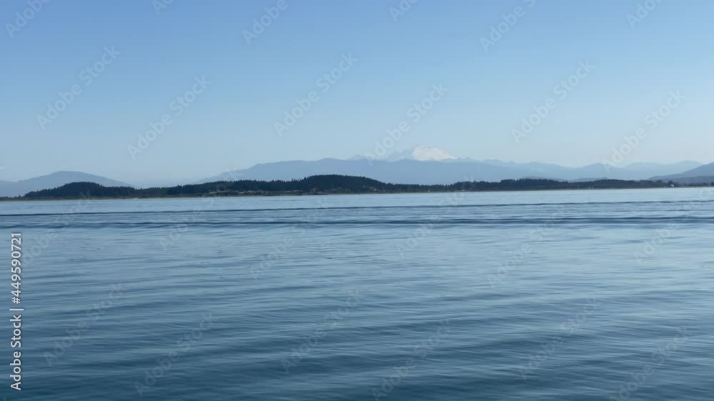 View from sailboat of Mount Baker and Cascade Mountain Range on beautiful blue sky day while underway transiting in Puget Sound.